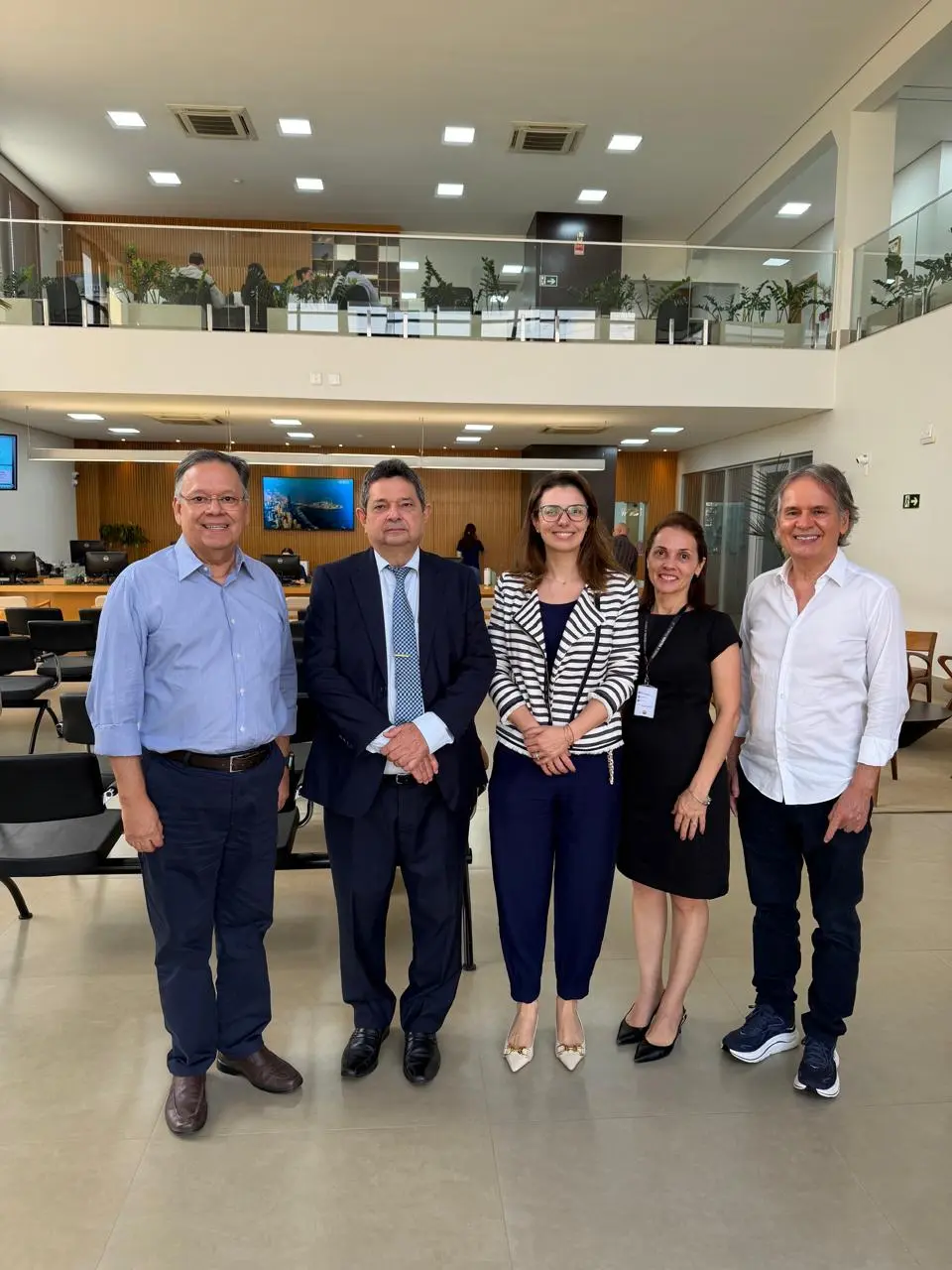 O delegatário do 1º Ofício de Sorriso, Haroldo Canavarros, o corregedor, desembargador José Luiz Leite Lindote, a juíza auxiliar da Corregedoria Myrian Pavan Schenkel e equipe posam lado a lado em ambiente interno, com mesas, cadeiras e estações de trabalho ao fundo. O espaço tem dois pavimentos, li