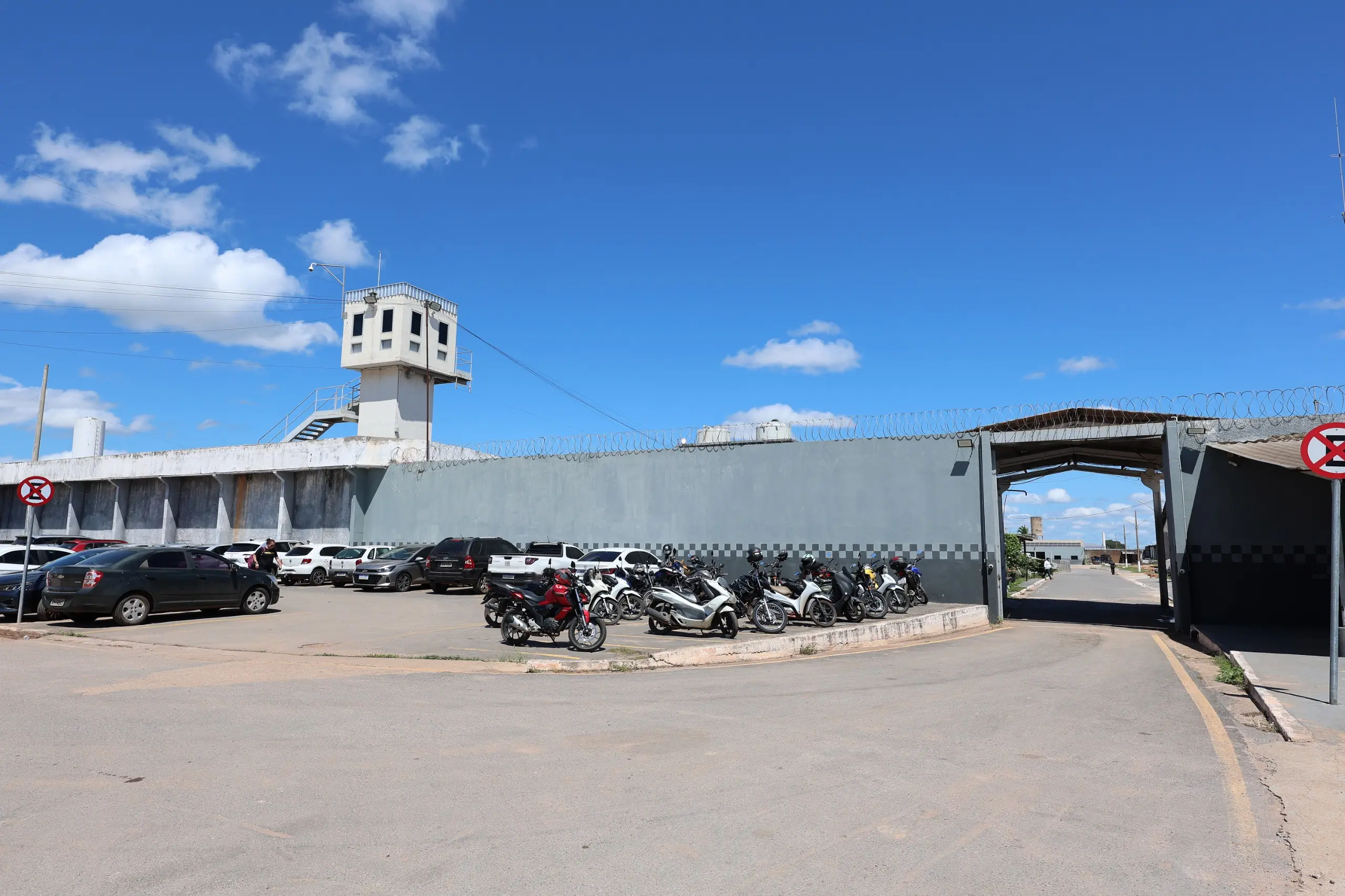 Área externa da Penitenciária Central do Estado, em Cuiabá. O local possui muro alto com cerca de segurança, guarita de vigilância e veículos estacionados na entrada.