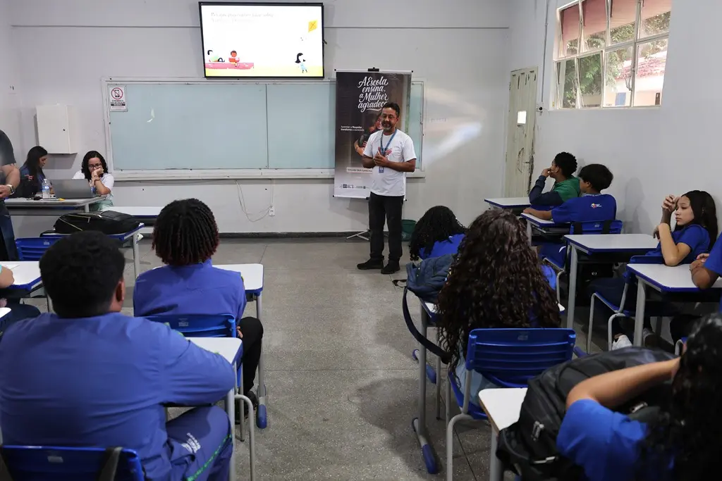 Foto horizontal em plano aberto que mostra a sala de aula cheia de alunos assistindo a palestra do servidor da Cemulher, Cristian Pereira, sobre violência contra a mulher. 