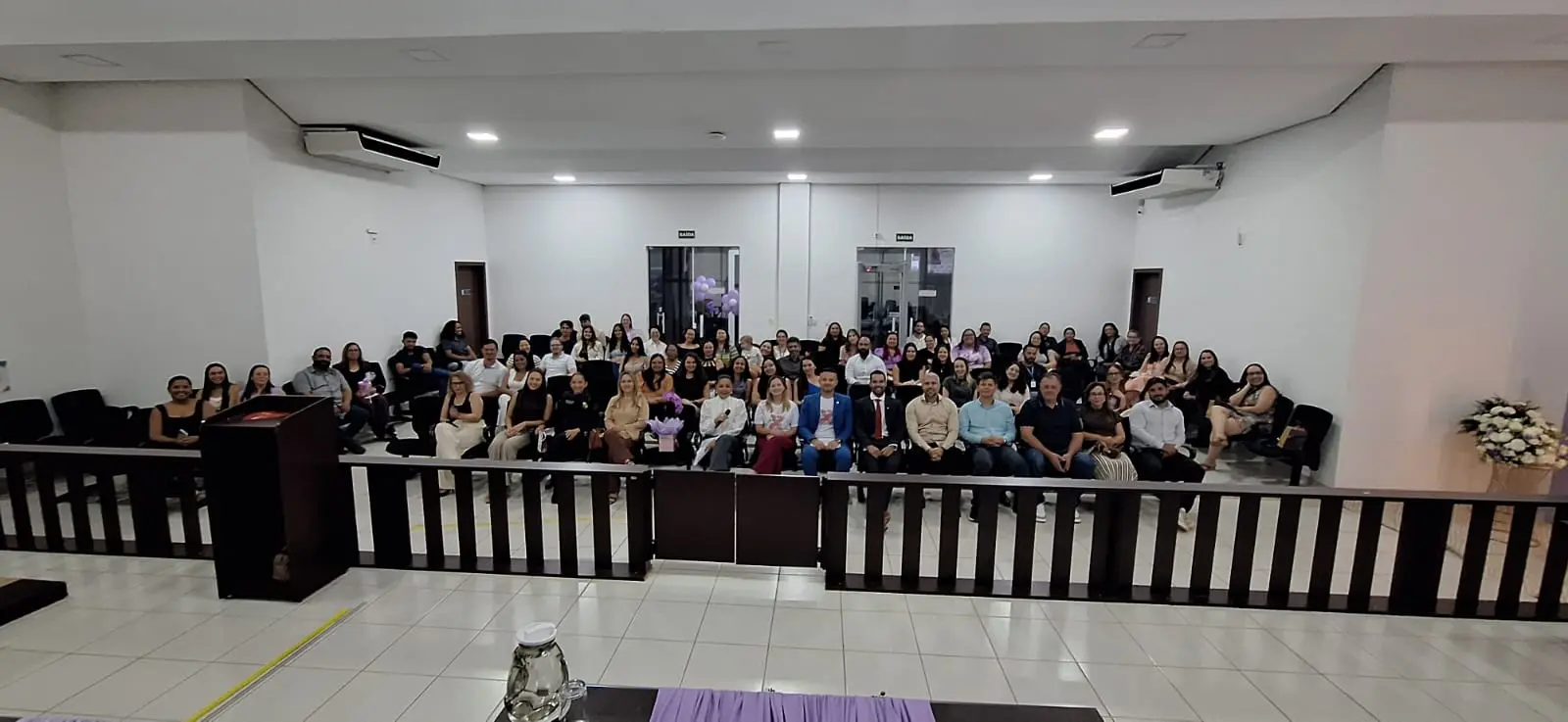 Foto horizontal em plano aberto que mostra a plateia do plenário do tribunal do júri cheio de pessoas, participantes do evento alusivo ao Agosto Lilás.