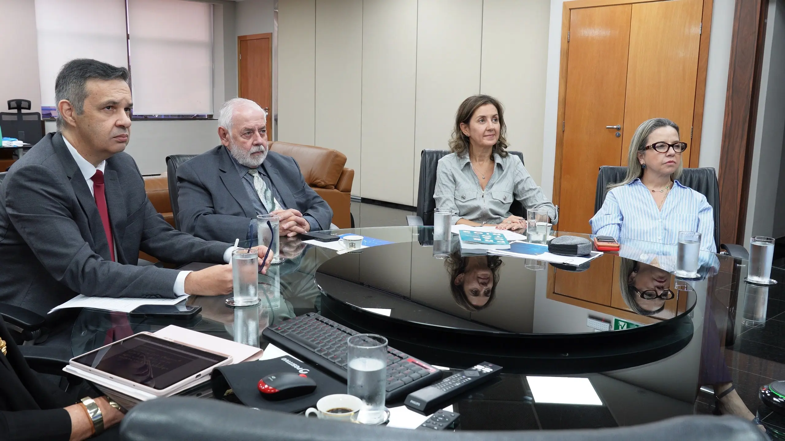 Autoridades do Tribunal participam de reunião estratégica em sala institucional, acompanhando apresentação exibida em grande monitor. O encontro debate diretrizes e metas do planejamento estratégico do Judiciário mato-grossense.