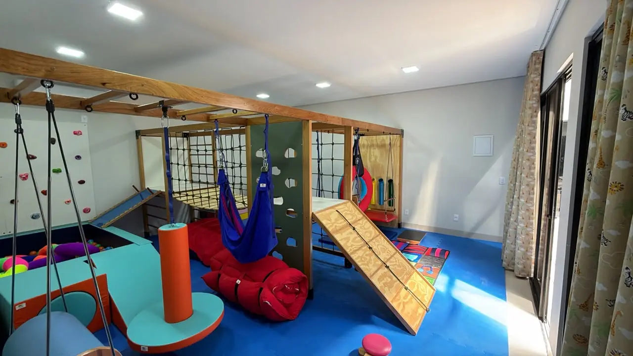 Espaço interno do Centro de Autismo Silvana Prado, equipado para atividades terapêuticas e multissensoriais. O ambiente conta com estruturas de madeira, redes, balanços, piscina de bolinhas, parede de escalada e outros equipamentos destinados ao desenvolvimento de habilidades motoras e sensoriais.
