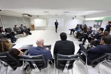 Homem com traje social, em ambiente interno e fundo desfocado. A imagem destaca o rosto e a parte superior da vestimenta, em composição formal e institucional. Ele sorri para a foto.