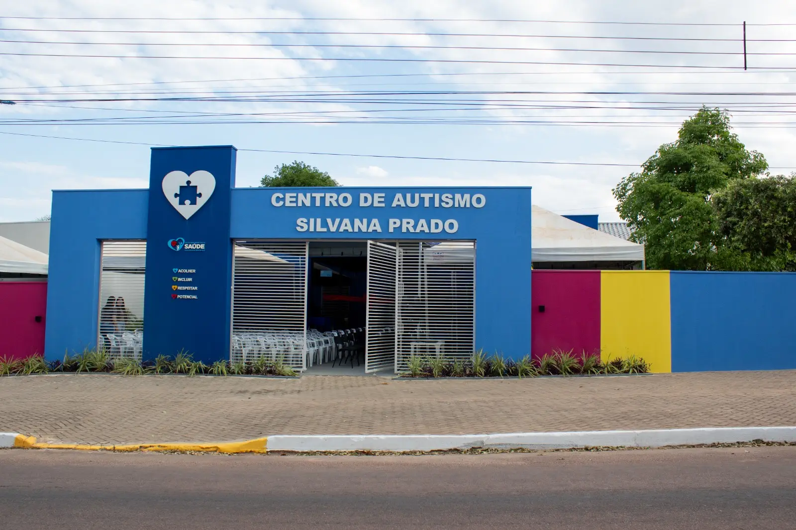 Fachada do Centro de Autismo Silvana Prado, em Guarantã do Norte. O prédio possui estrutura predominantemente azul, com detalhes coloridos em rosa e amarelo e identificação do Centro na entrada.