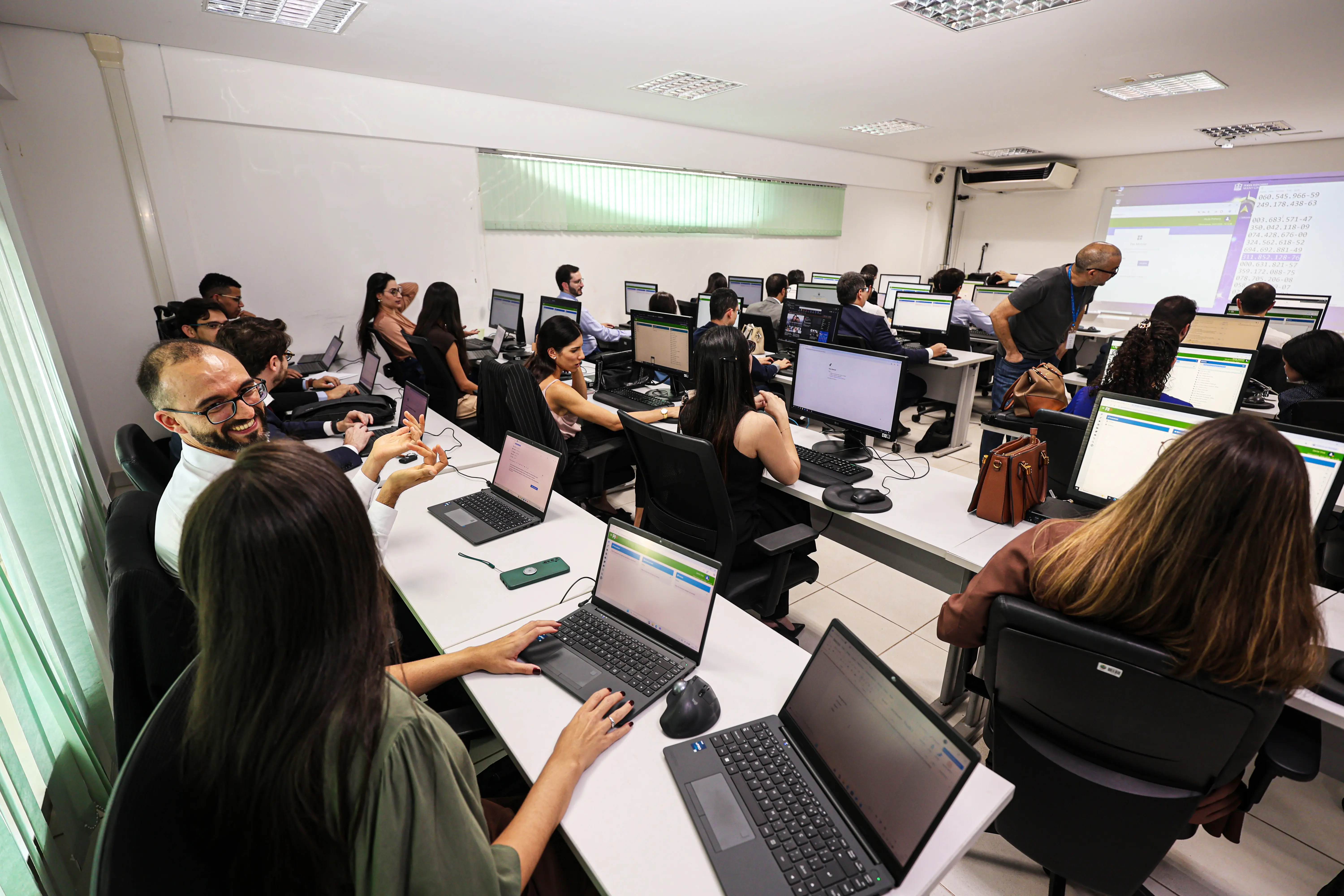 Participantes acompanham capacitação prática do PJe em laboratório de informática, com magistrados e servidores utilizando computadores e recebendo orientações do instrutor durante o treinamento.