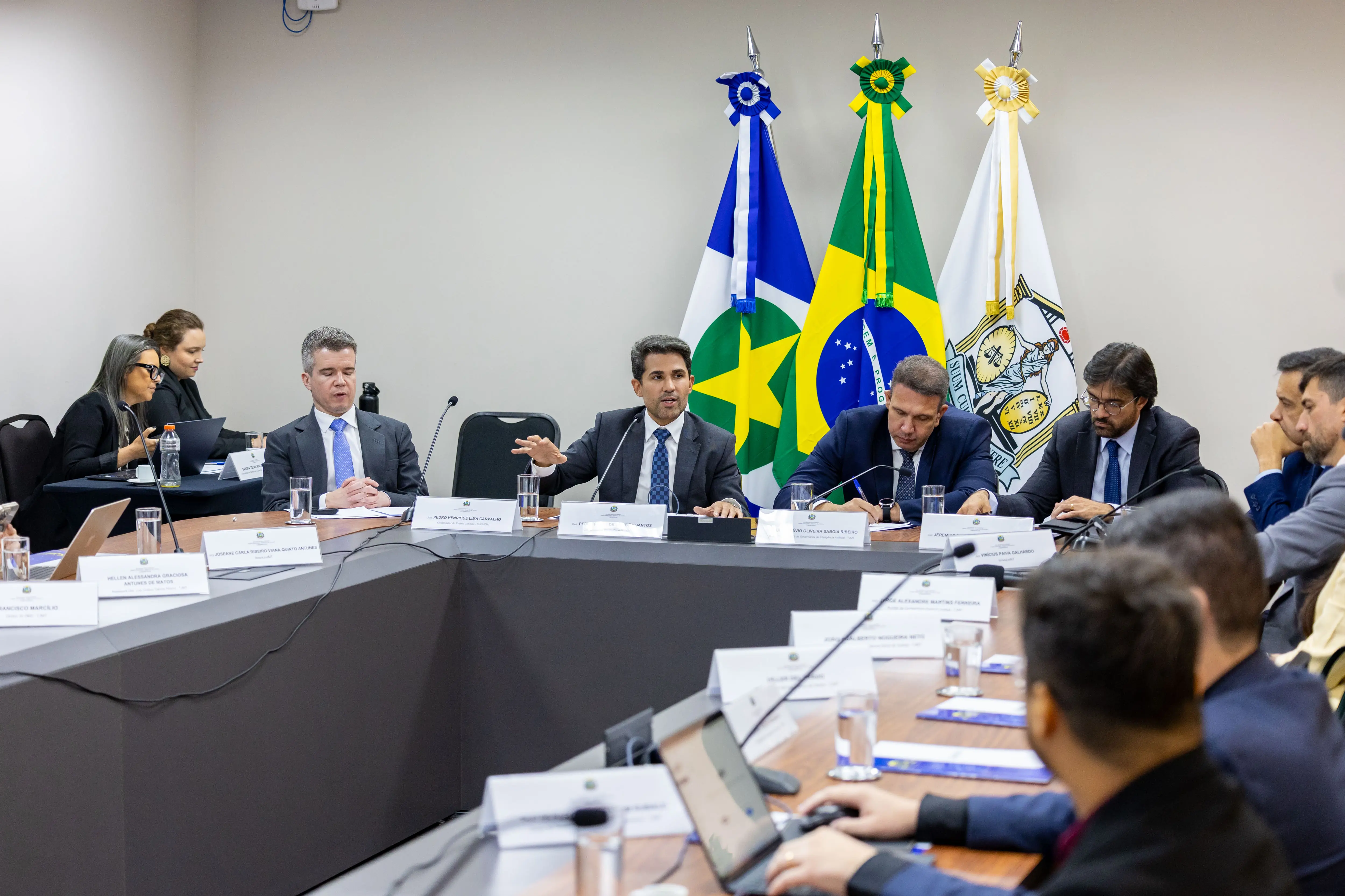 Homens de terno sentados em uma mesa em formato de 