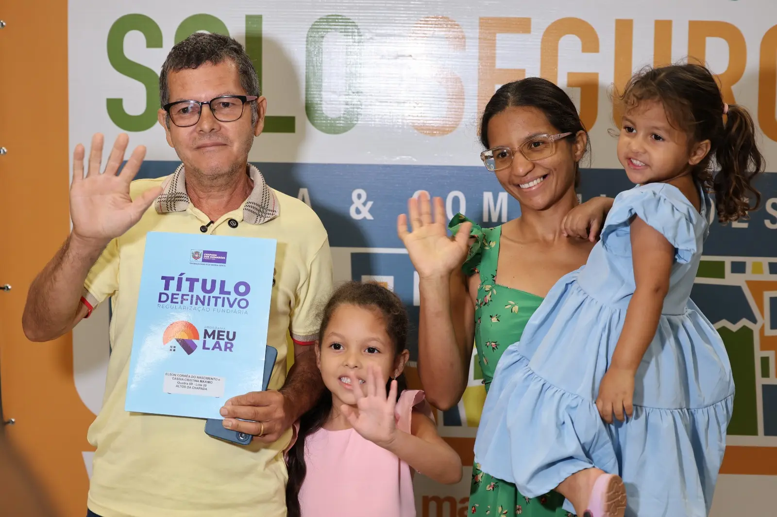 O morador Elson Corrêa do Nascimento posa ao lado da esposa e das duas filhas após receber o título definitivo de regularização fundiária do imóvel da família, durante cerimônia do programa Solo Seguro - Favela e Comunidades 2026, realizada em Chapada dos Guimarães. 