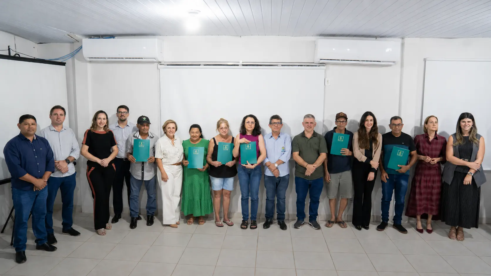 Moradores do Loteamento Curió e autoridades posam para foto durante cerimônia de entrega de títulos definitivos de regularização fundiária realizada em Nova Mutum.