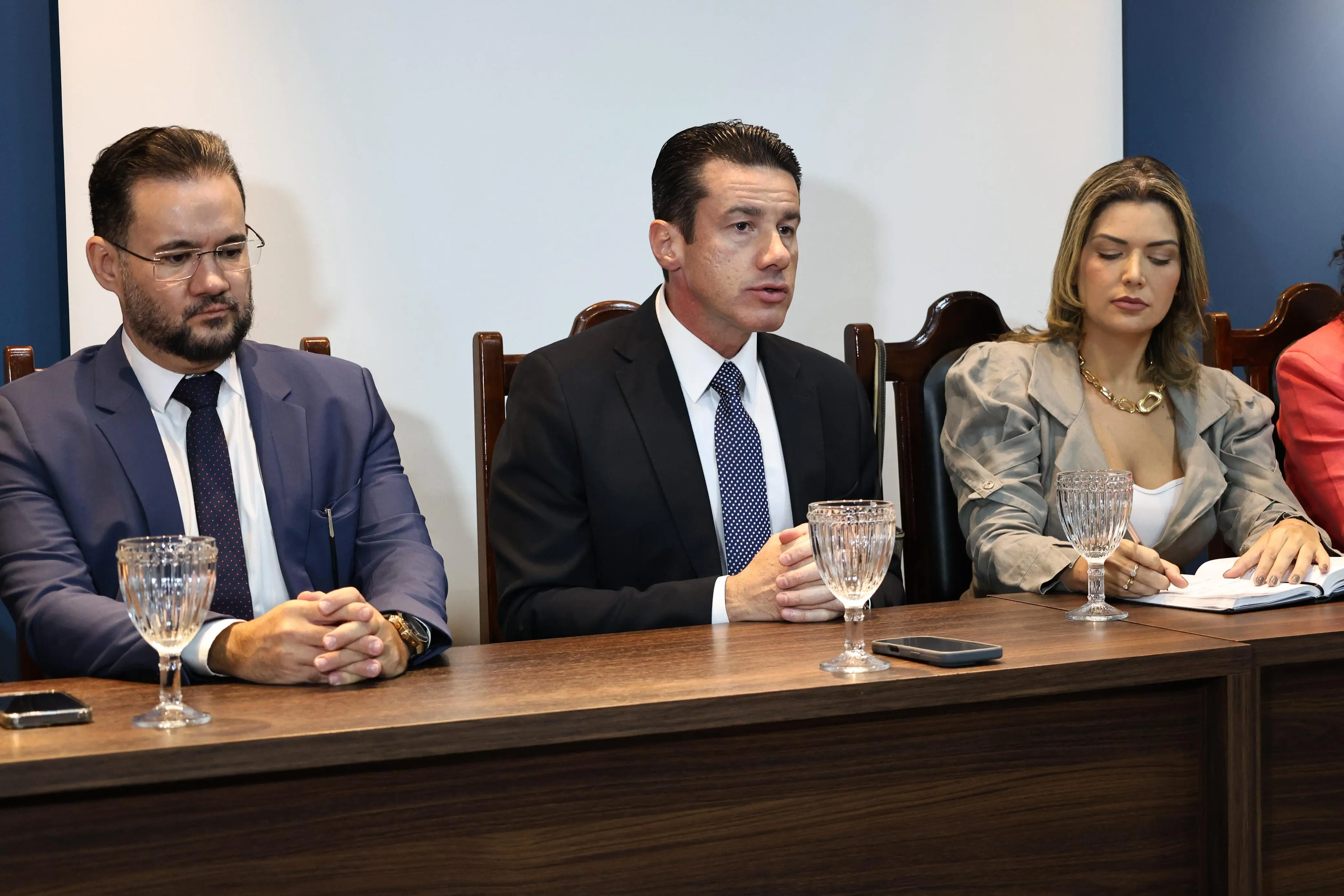 Desembargador Rodrigo Curvo, ladeado pelo juiz Bruno D'Oliveira e pela vice-presidente da OAB Rondonópolis, Priscila Raimundi, sentados em uma mesa.