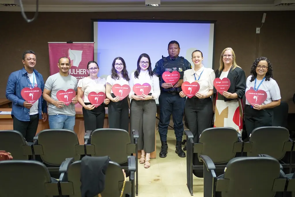 Foto de várias autoridades posando para a foto sorrindo. Eles estão segurando corações de papel.