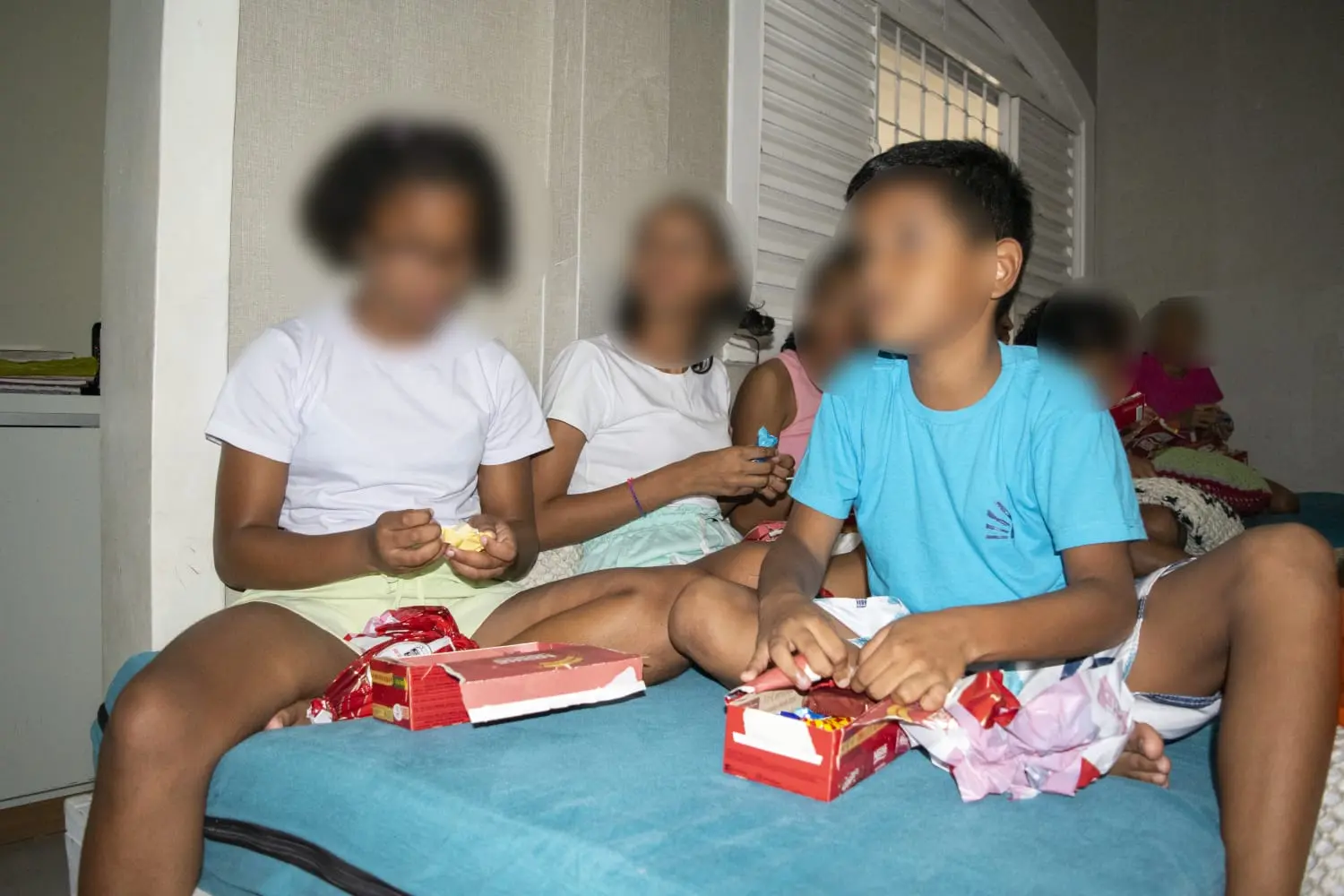 Imagem mostra uma menina e um menino abrindo caixas de bombons.