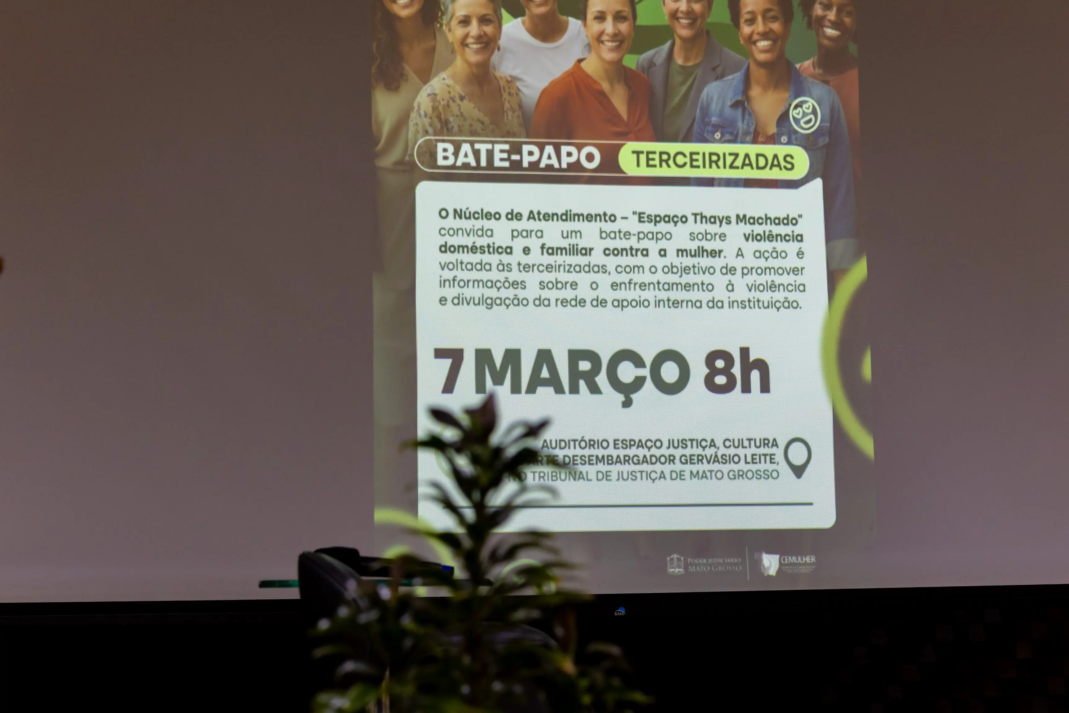 Telão de apresentação exibe slide do evento “Bate-Papo”, com data marcada para 7 de março às 8h. A projeção aparece ao fundo enquanto participantes acompanham a atividade no auditório.