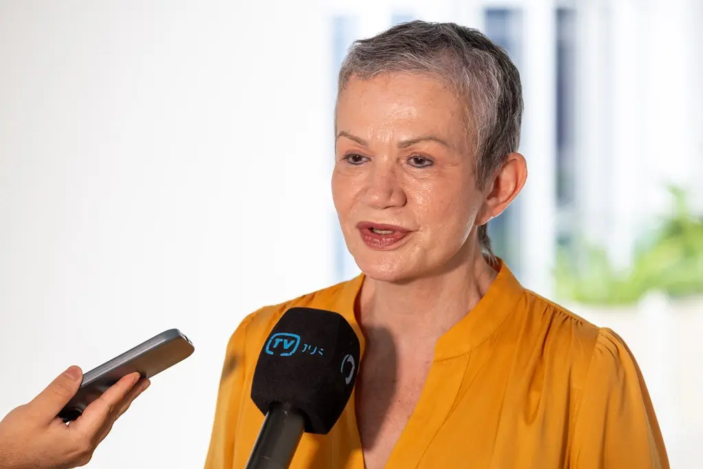 Foto horizontal em plano fechado que mostra a juíza Maria Rosi de Meira Borba durante entrevista à TV.Jus. Ela é uma mulher branca, de olhos castanhos, cabelos grisalhos e bem curtos, usando camisa na cor amarelo ouro.