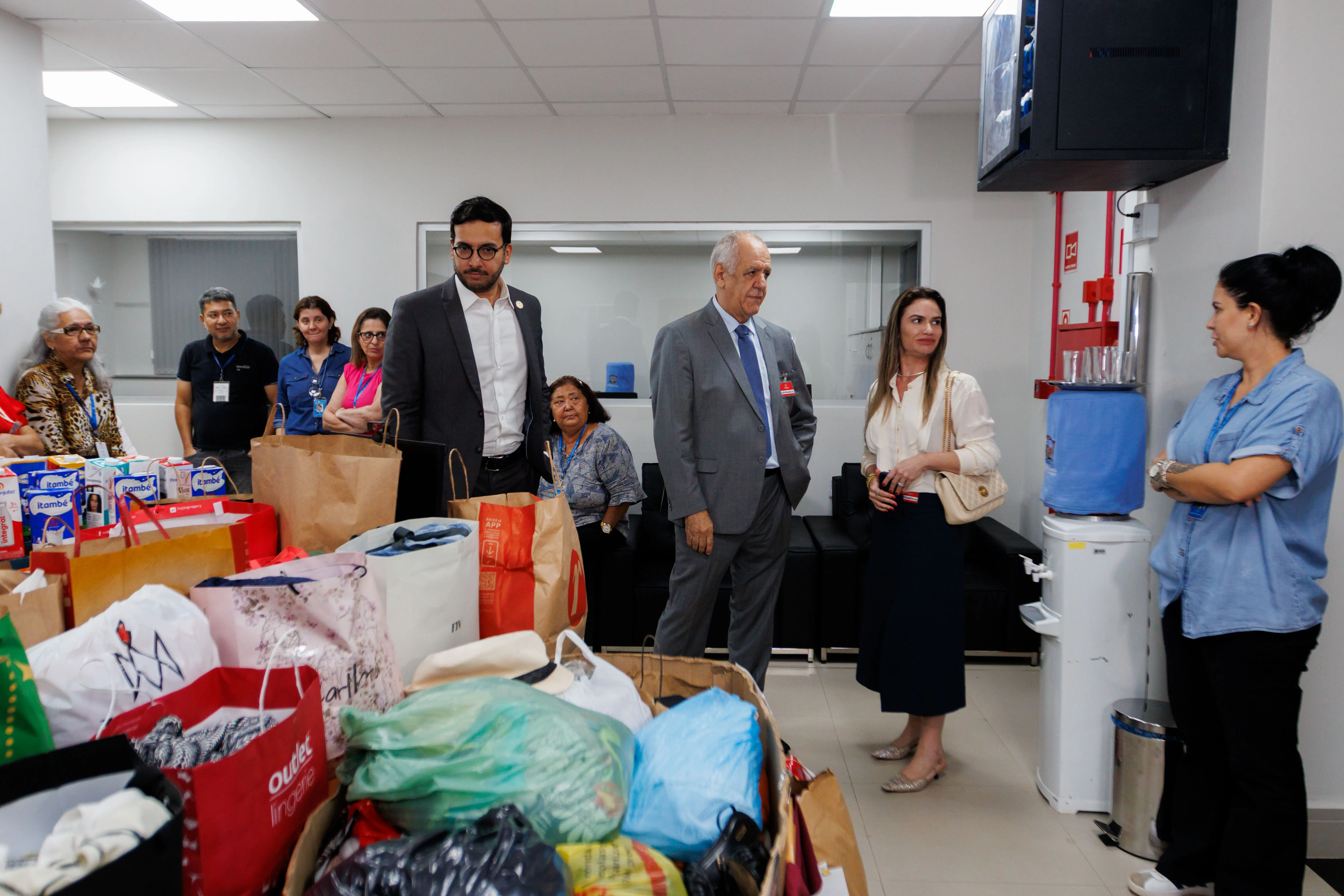 Várias pessoas em pé observam os i tens doados para campanha à Casa de Amparo. Na foto aparecem Pedro Calazans, Ussiel Tavares, a advogada Aline e demais servidores do TJ