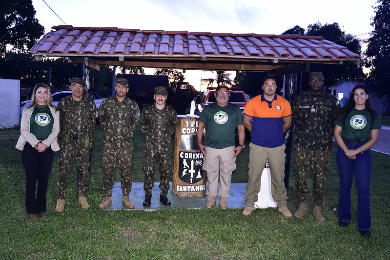 Militares do Exército, juiz e assessoras da Justiça Comunitária e um representante da Defesa Civil posam para a foto em um monumento do Pelotão de Fronteira Corixa.