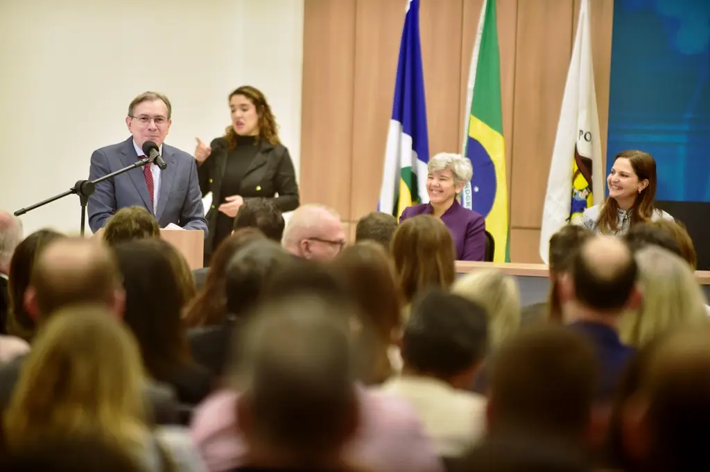 Desembargador Sebastião Arruda tem cabelos castanhos curtos e óculos, está posicionado para a direita. Ele usa um terno cinza e uma gravata bordô com pontos brancos