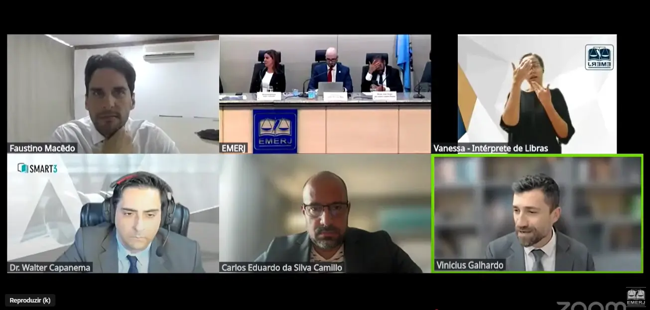 Print de tela que mostra uma videoconferência dividida em seis quadros. Em um deles, aparece o juiz Vinicius Paiva falando.