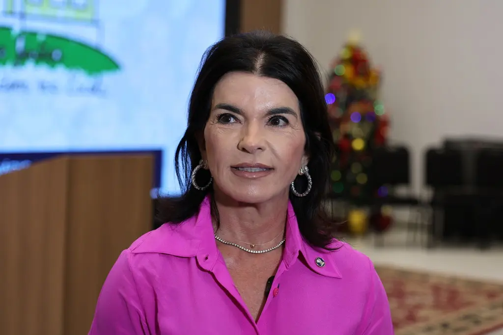 Juíza Jaqueline Cherulli. Ela é uma mulher branca, de cabelos e olhos escuros, usando camisa na cor pink.