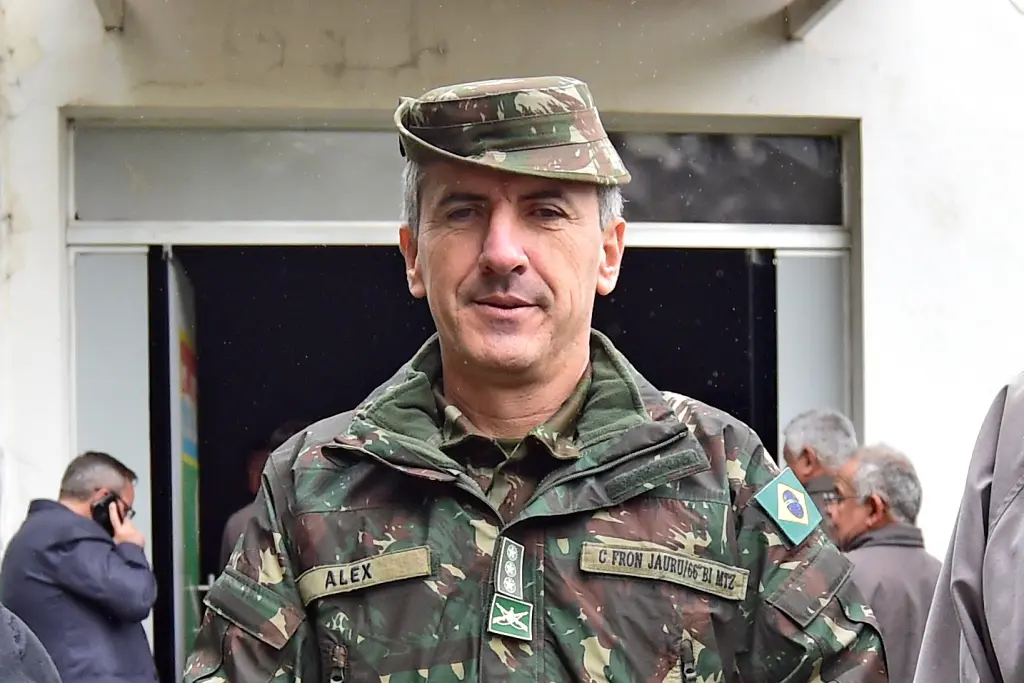 Coronel Alex, comandante do Comando de Fronteira Jauru/66º Batalhão de Infantaria Motorizada, posa para a foto, sorrindo. Ele é um homem branco, de cabelos grisalhos, fardado com roupas e chapéu camuflados.