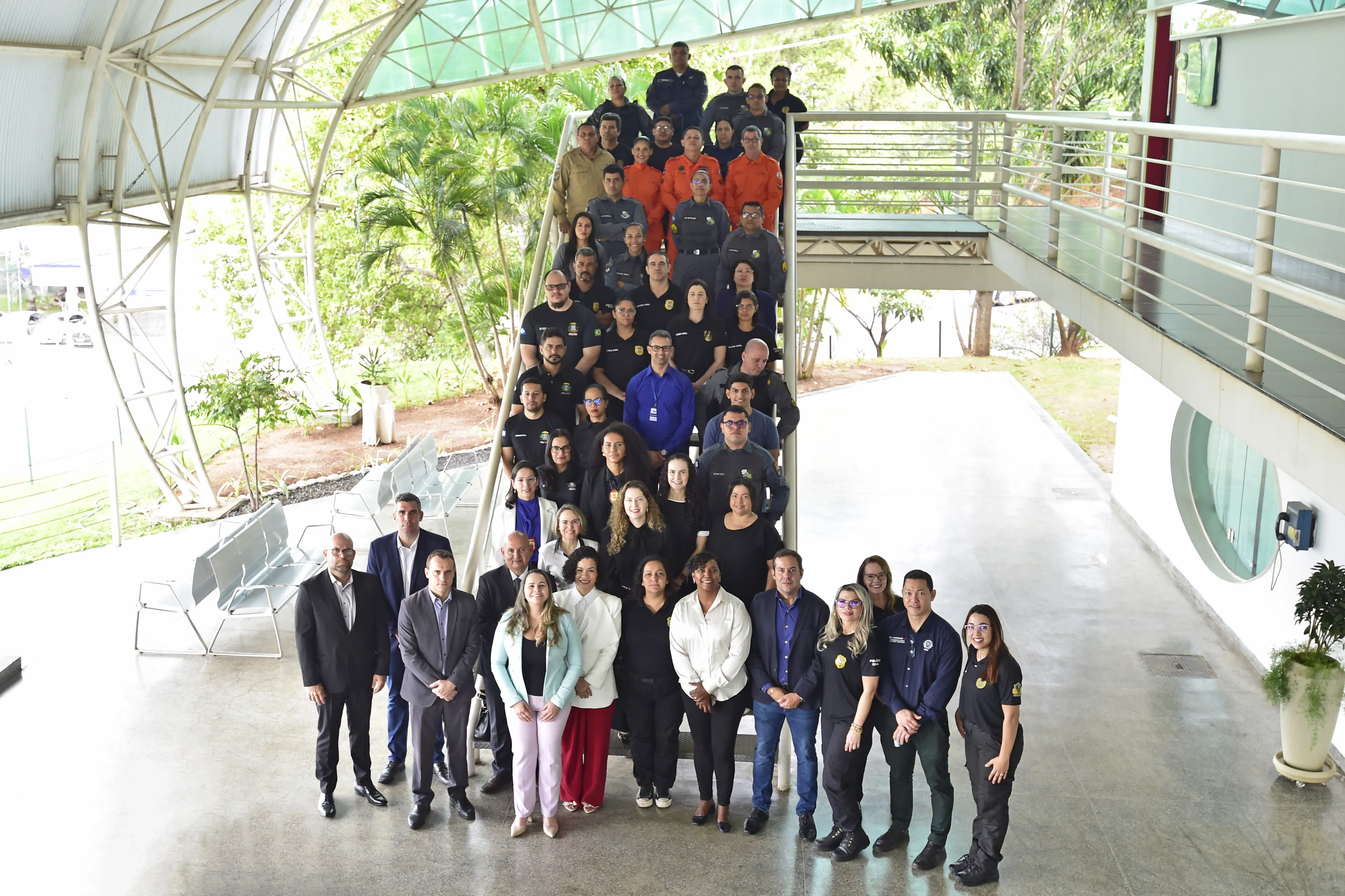 Foto em plano aberto que mostra todos os participantes do curso posando para a foto na escadaria que fica no saguão da Escola dos Servidores. 