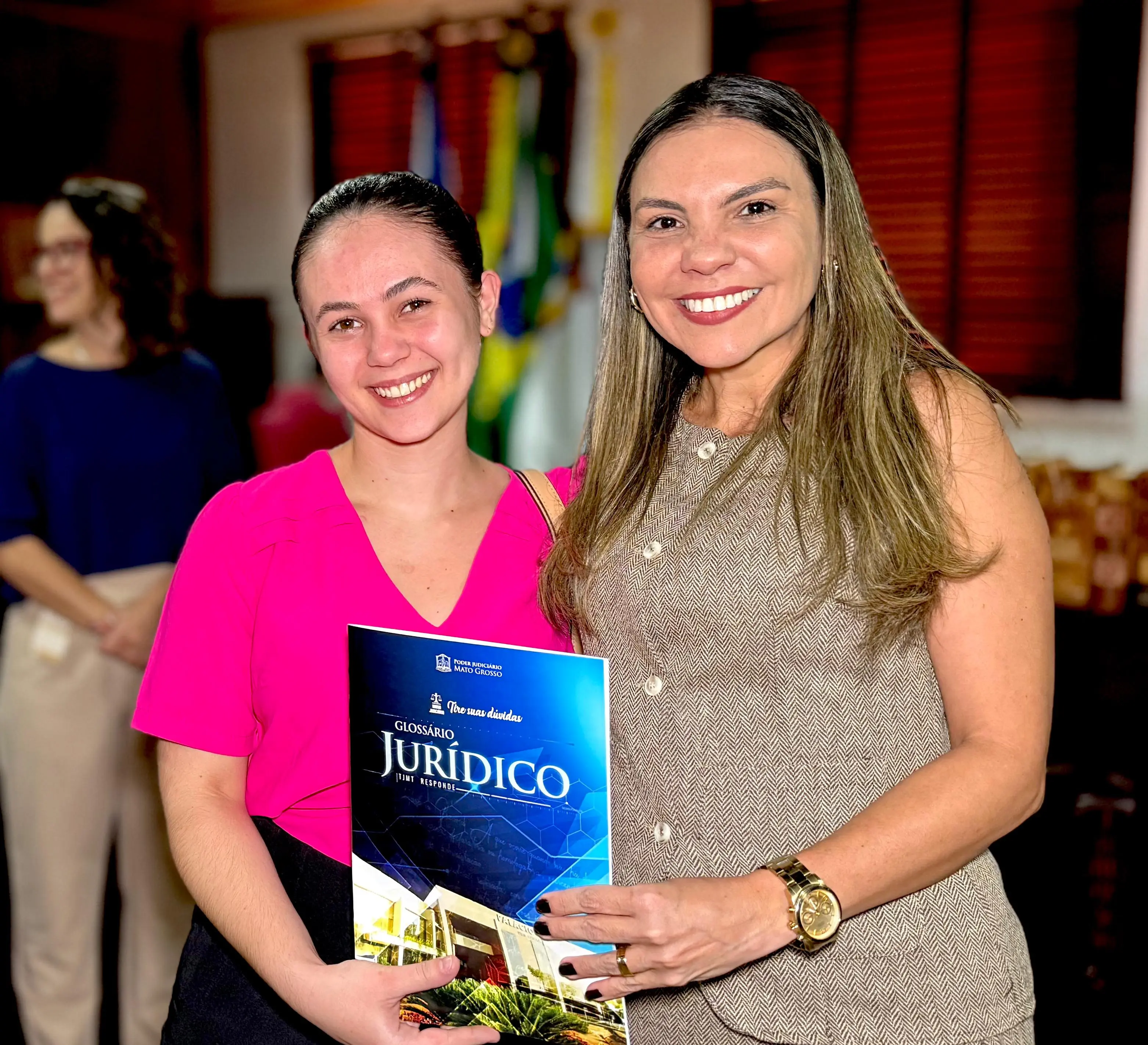 Juíza Henriqueta Chaves entrega o Glossário Jurídico a uma estudante de Direito. As duas sorriem para a foto.