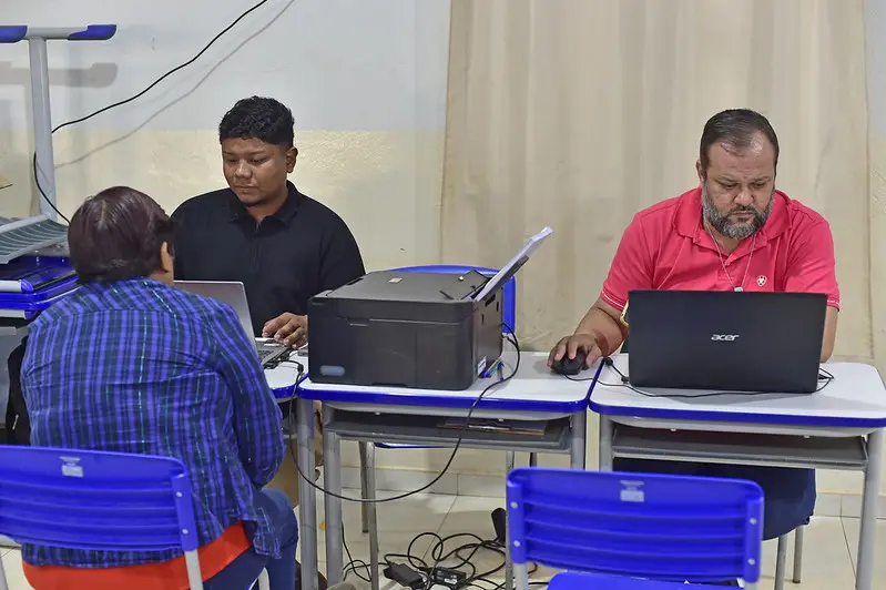 Foto que mostra atendimento de cidadão por servidores, em uma sala de aula.