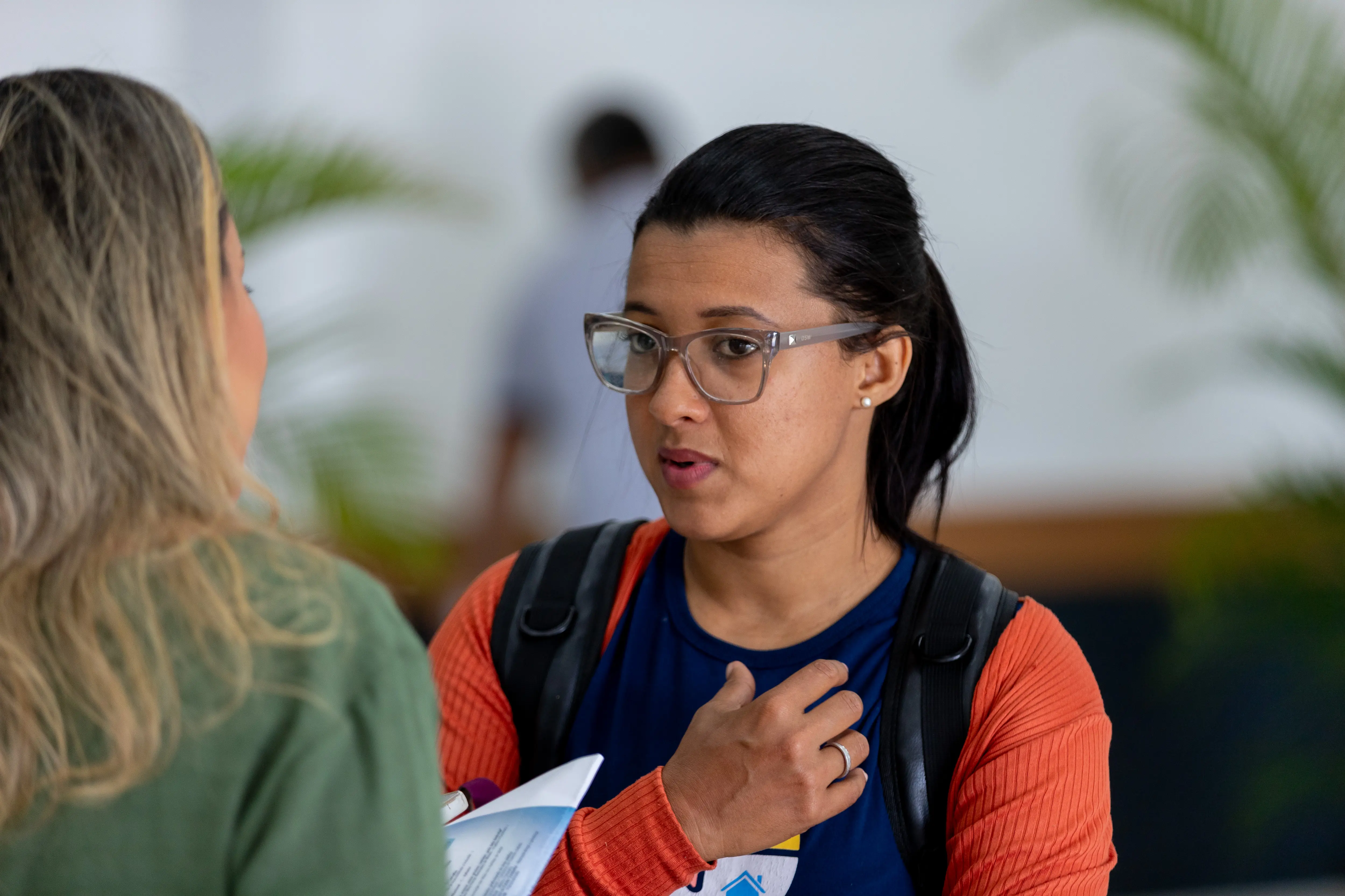 Daiane, mãe atípica, que aprticipou do TJMT Inclusivo em Sorriso. Ela é uma mulher morena, cabelos lisos e pretos que estão presos num rabo de cav alos. Usa óculos de grau, camiseta azul com manga laranjada
